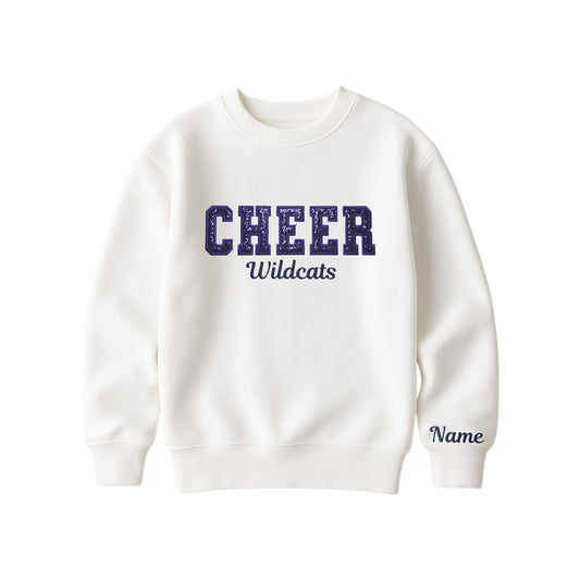 bleached linen boxy crewneck sweatshirt with navy glitter applique embroidery reading cheer with wildcats embroidered in a script font underneath, and an optional name embroidery in a script font on the left sleeve