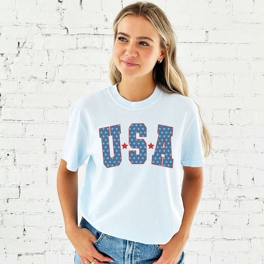 woman wearing a chambray comfort colors t-shirt featuring a large vintage inspired USA star printed design