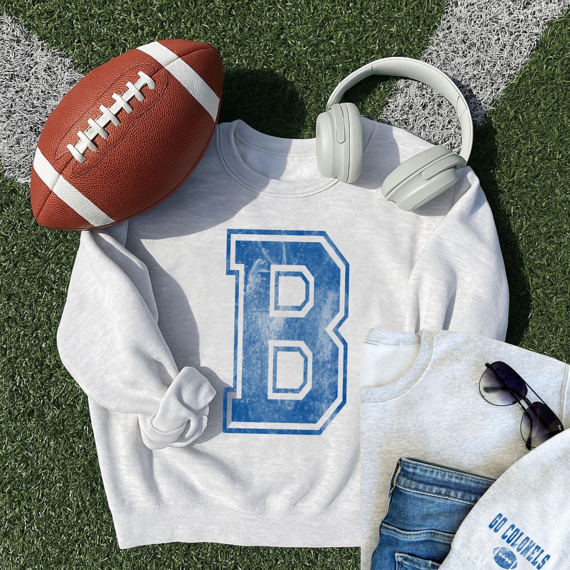 ash crewneck sweatshirt with printed distressed varsity inspired B in blue ink and another small outfit layout featuring an ash crewneck with go colonels and a football printed on the left sleeve cuff