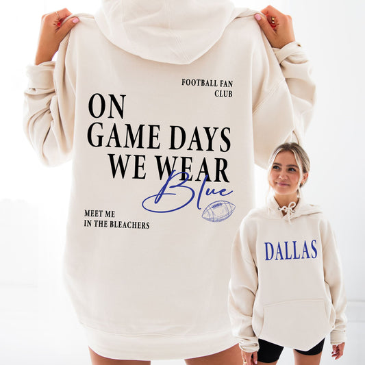 White hoodie with text 'On game days we wear blue, meet me in the bleachers' and 'Dallas' on a white background.