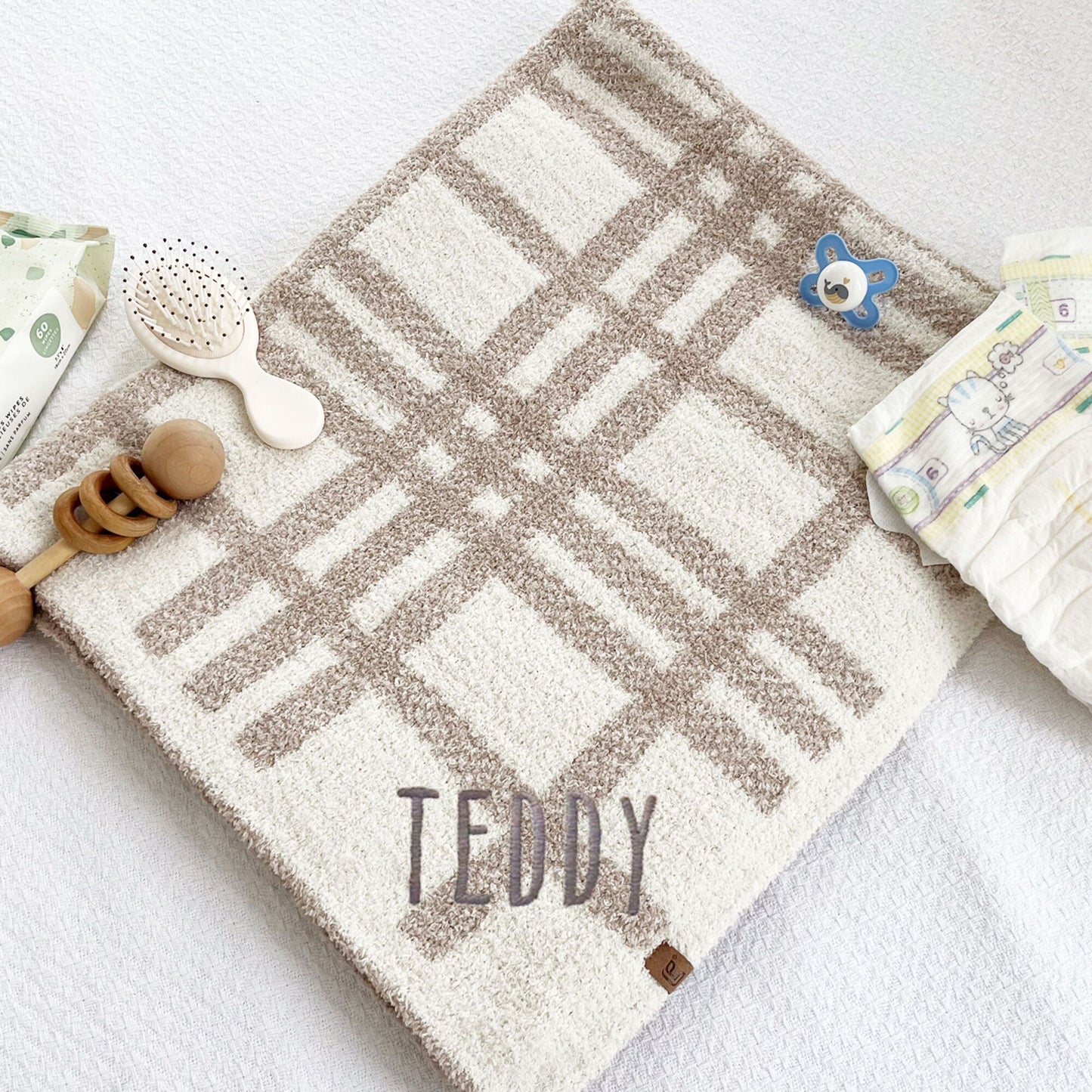 ultra soft cream and tan plaid baby blanket with custom name embroidered on the corner in Handicraft font and gray thread