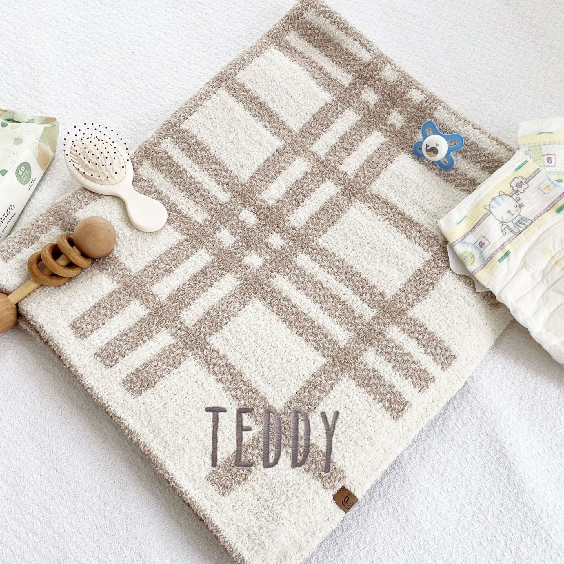 ultra soft cream and tan plaid baby blanket with custom name embroidered on the corner in Handicraft font and gray thread
