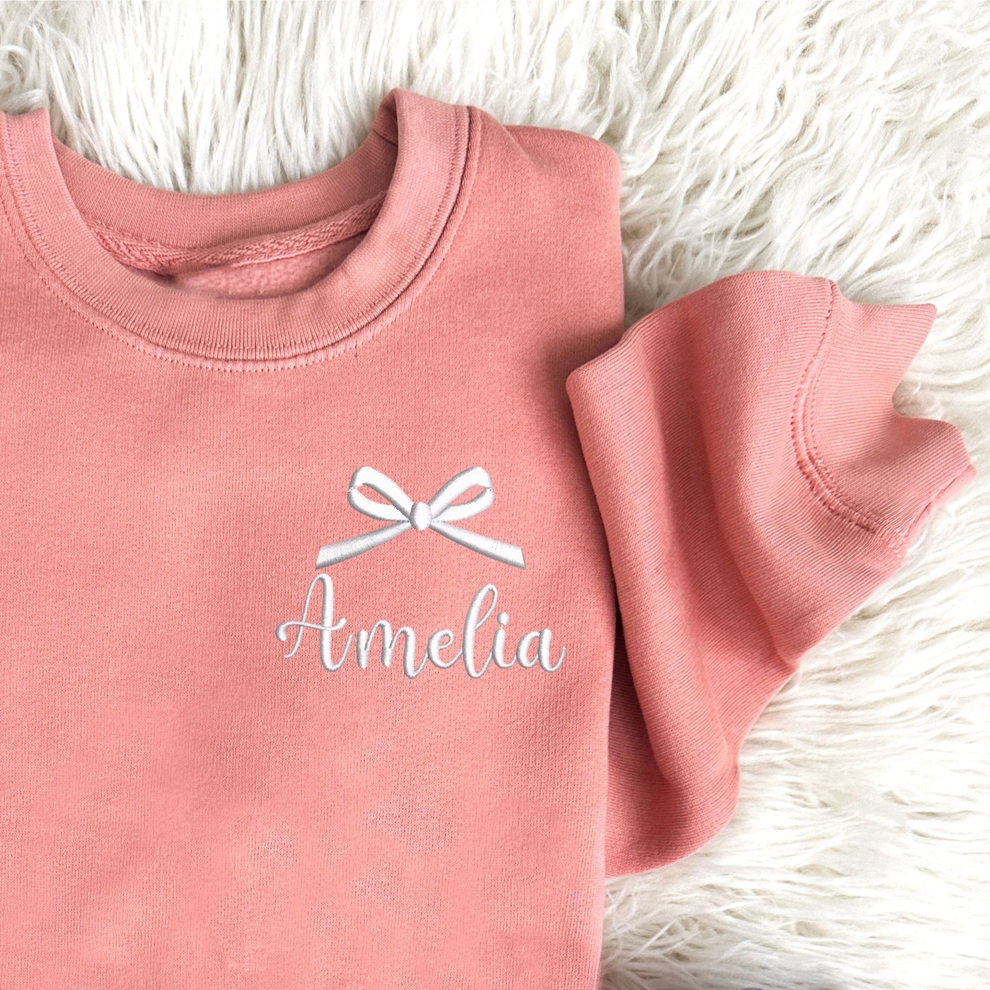 mauve youth crewneck sweatshirt with embroidered bow and name design on the left chest in white thread