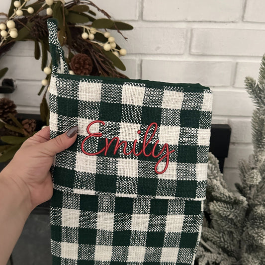 green and white buffalo check stocking with custom name embroidered in blithe font and red thread.