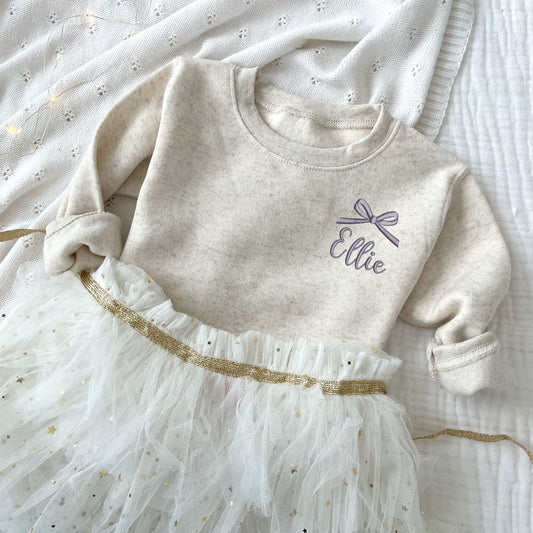 natural heather toddler crewneck with embroidered name and bow on the left chest in smoky orchid thread.