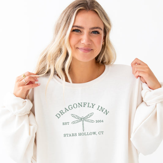 girl wearing an oversized sweet crewneck sweatshirt with Dragonfly Inn Stars Hollow, CT embroidered design in eucalyptus thread