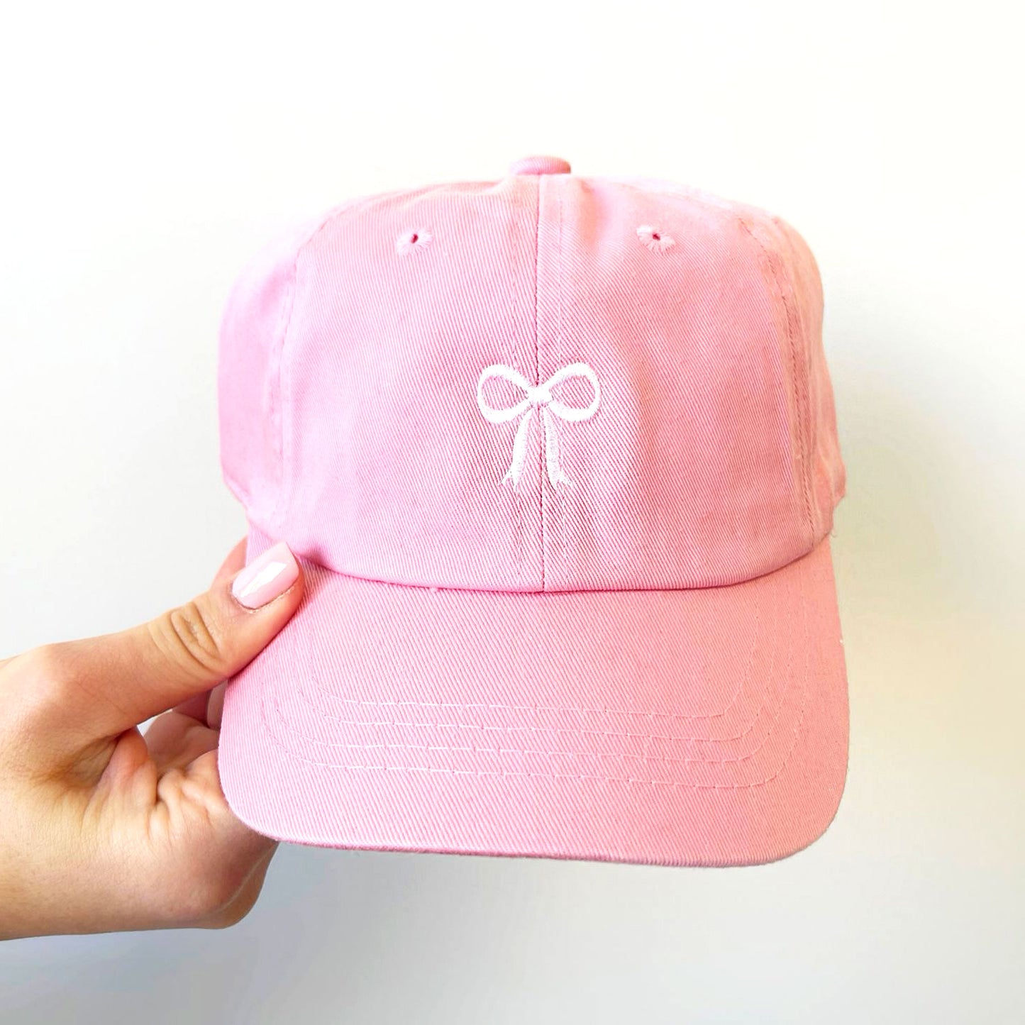 pink hat with a dainty white ribbon bow embroidered on the center