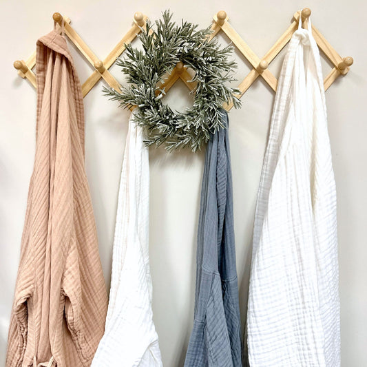 Wooden peg rack with robes and a wreath on a white wall