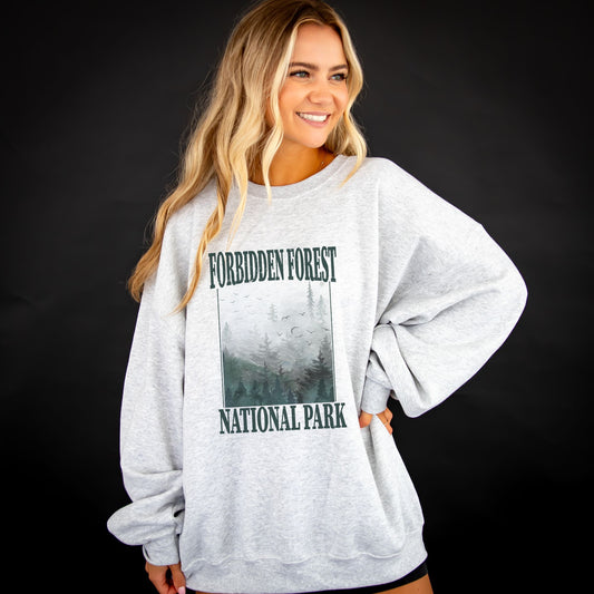 girl wearing an oversized ash crewneck sweatshirt with a distressed forbidden forest national park print