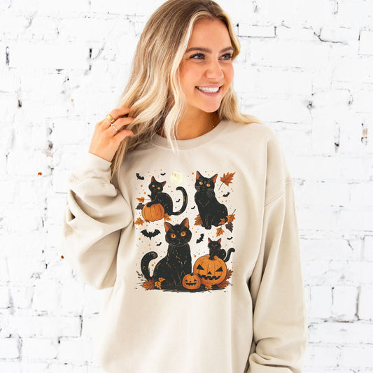 young woman wearing a sand crewneck sweatshirt with a vintage inspired black cat, jack-o-lantern, moon, leaves, and bat printed design