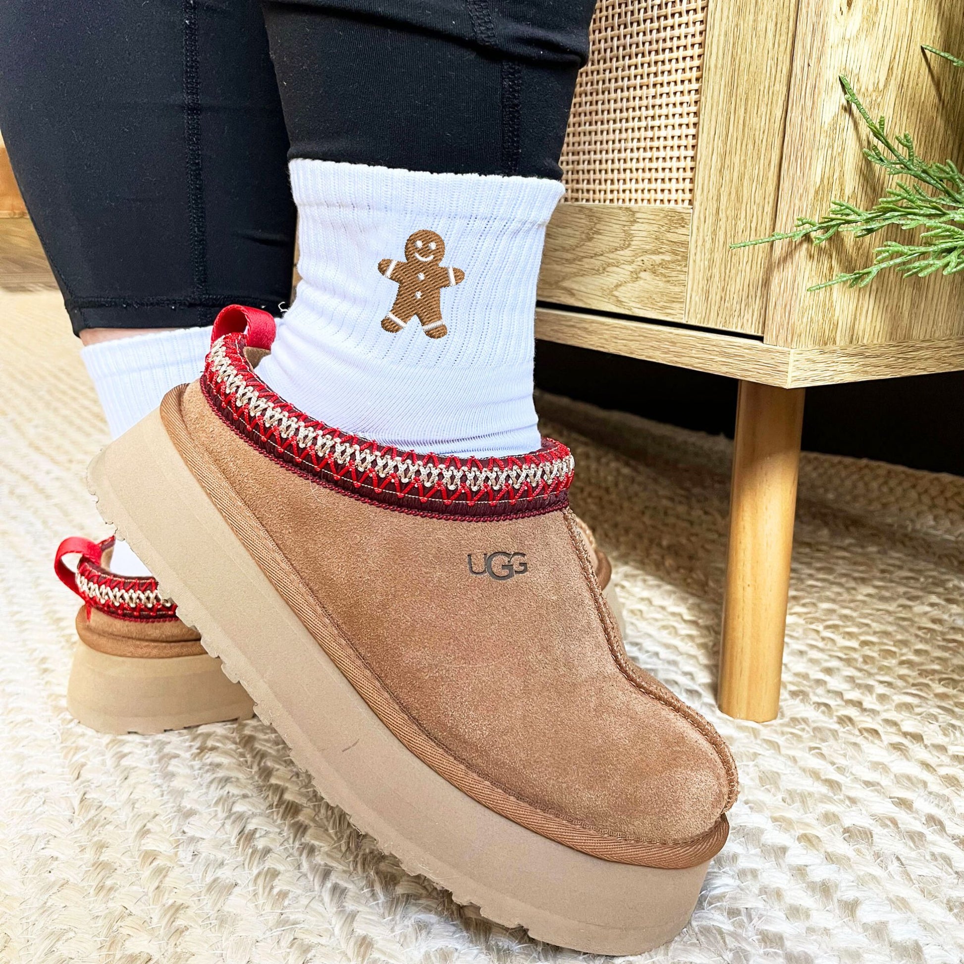 close up of someone wearing white crew socks with embroidered gingerbread man design with ugg slippers