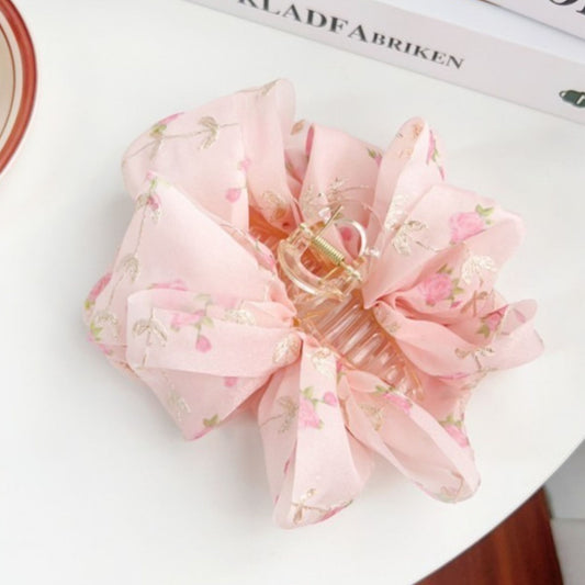 Pink floral hair clip on a white surface