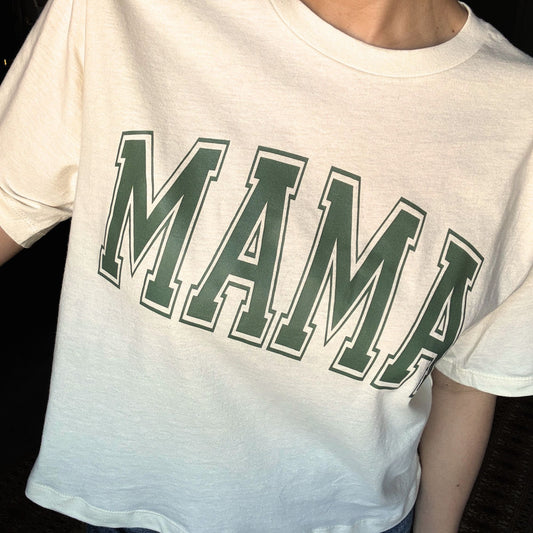 woman wearing a creme cropped t-shirt with custom printed mama design across the chest in hunter green ink