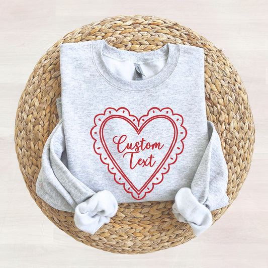 Gray sweatshirt with a red heart-shaped design and 'Custom Text' on a woven surface