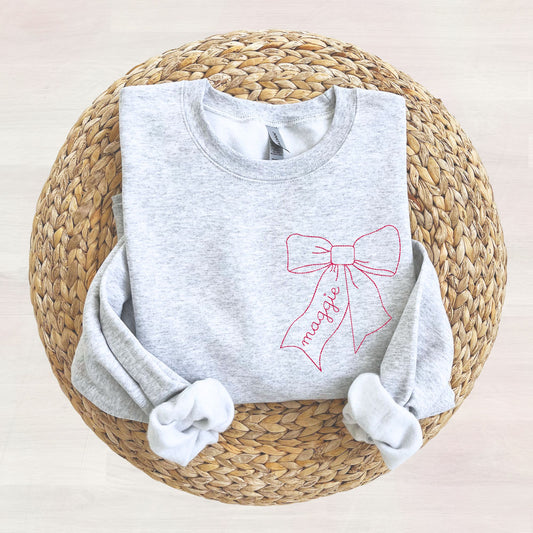 ash sweatshirt with a stitched raspberry pink bow name design on the left chest