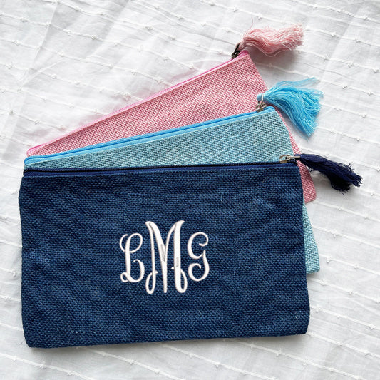 light pink, palace blue, and navy jute full zip pouches. navy features a white monogram in a traditional font