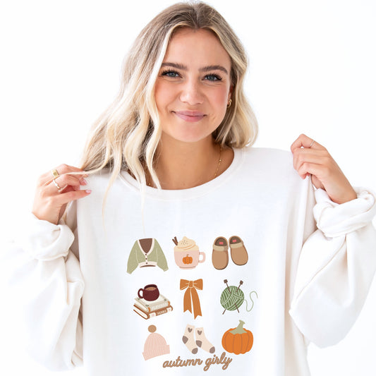 girl wearing a white crewneck sweatshirt with cozy, autumn girly fall icons printed in a grid style, including the following: sweater, pumpkin spice, slippers, books, bow, yarn, hat, socks, pumpkin