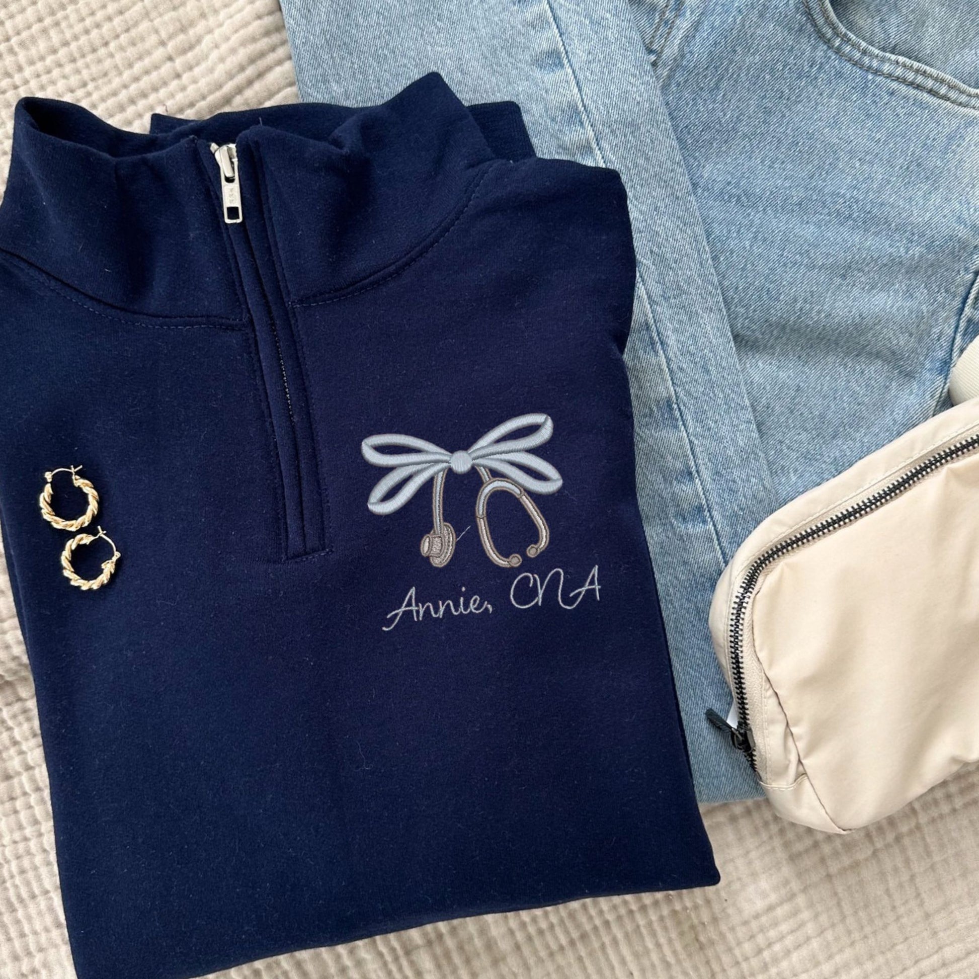 navy quarter zip sweatshirt with custom double loop bow stethoscope design with name embroidered on the left chest in powder blue thread