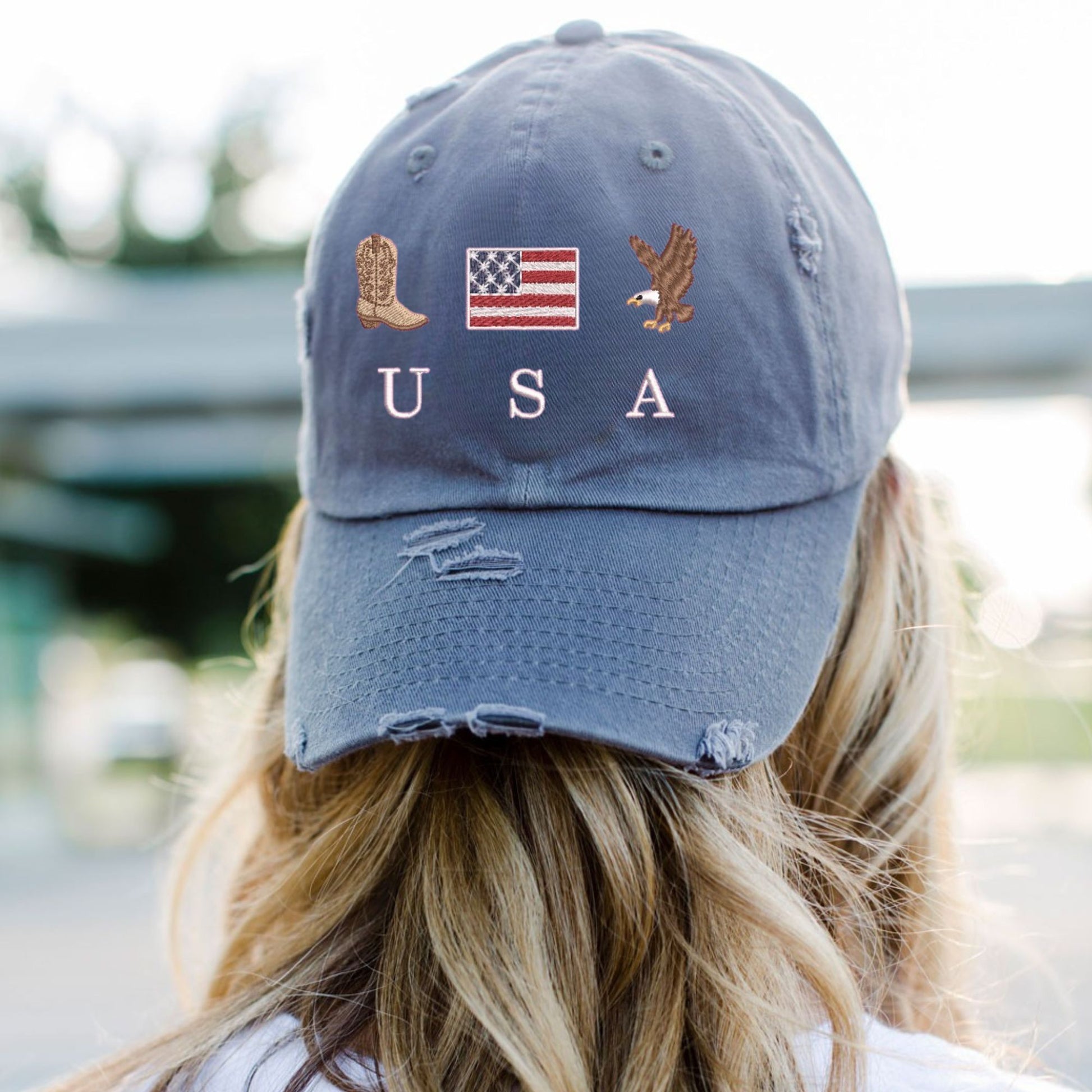 woman wearing a scotland blue distressed baseball cap with embroidered cowboy boot, american flag, eagle, and USA design