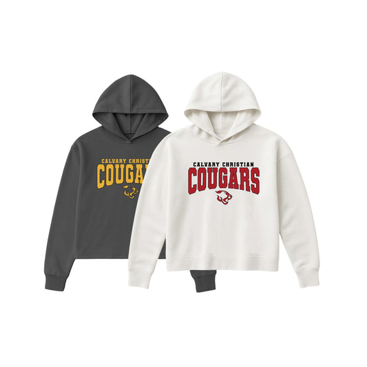 Two cropped hoodies shown on a plain white background: one dark charcoal gray hoodie with yellow and black 'Calvary Christian Cougar' text, and one off-white hoodie with red and black 'Calvary Christian Cougars' text and a small cougar graphic.