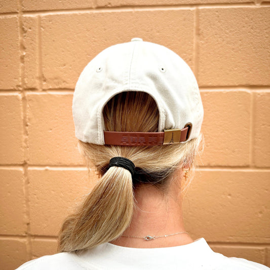 Back image of a person wearing a white cap with a brown strap