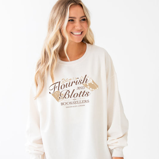 woman wearing an oversized sweet cream pullover sweatshirt with a flourish and blotts booksellers print