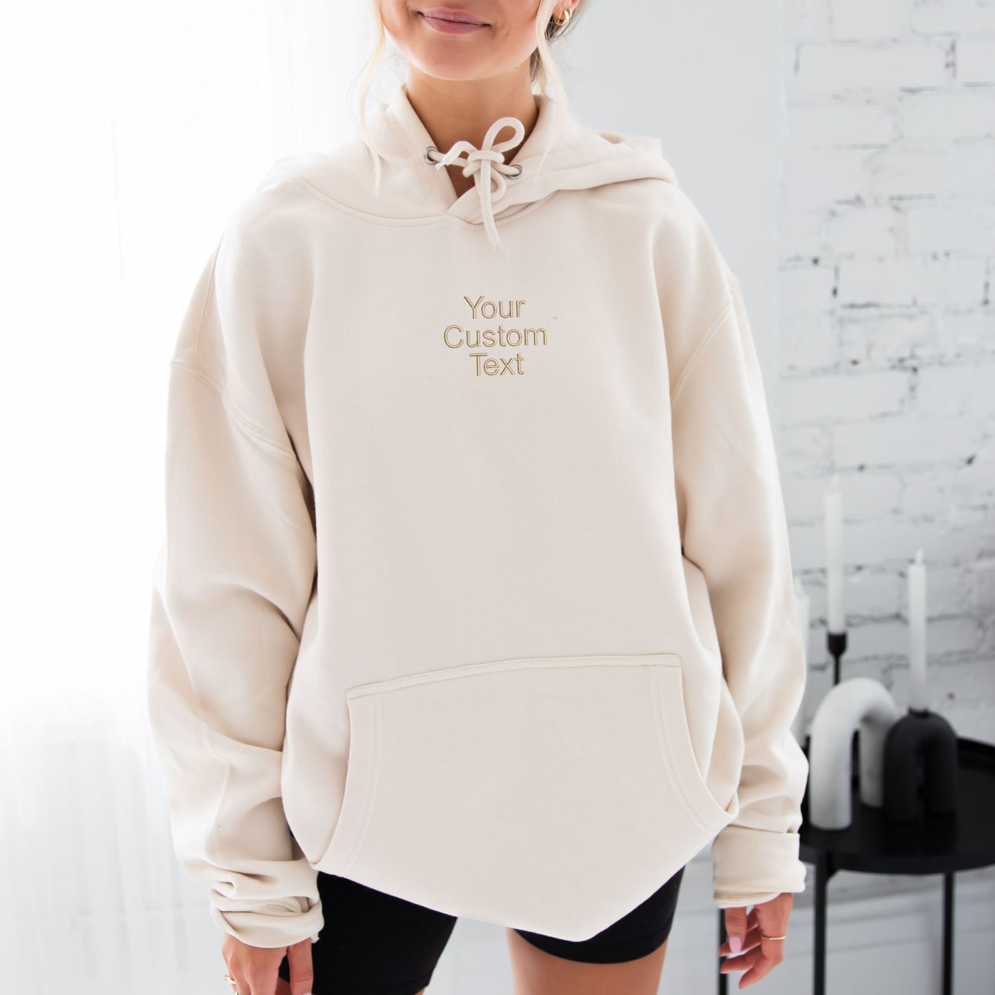 young woman wearing a sandshell hoodie with embroidered your custom text in camel thread