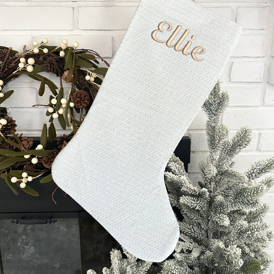 white and silver Christmas stocking with custom embroidered name in script font and camel thread