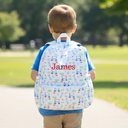 Child wearing a golf patterned backpack with 'James' on it in a park setting
