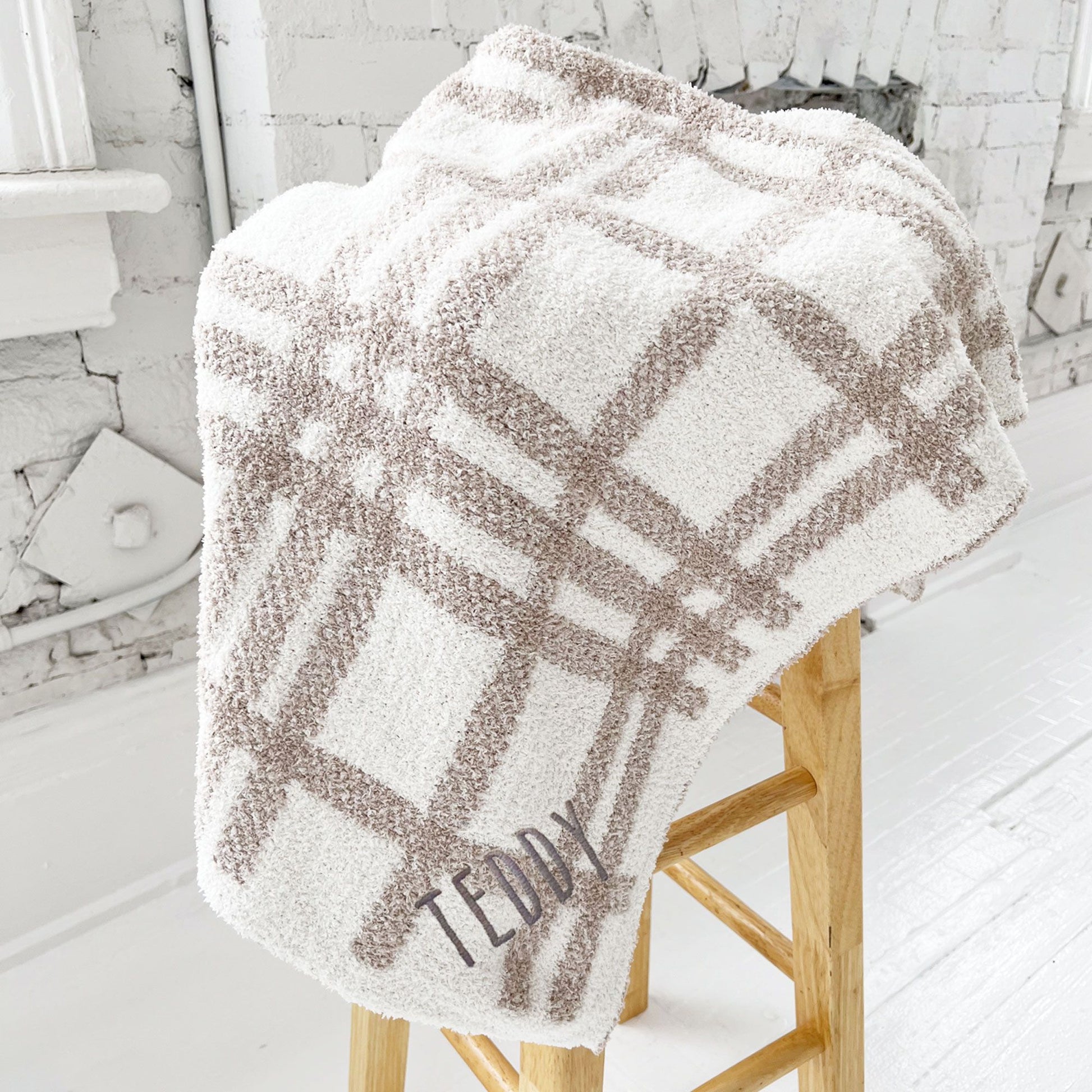 ultra soft cream and tan plaid baby blanket with custom name embroidered on the corner in Handicraft font and gray thread