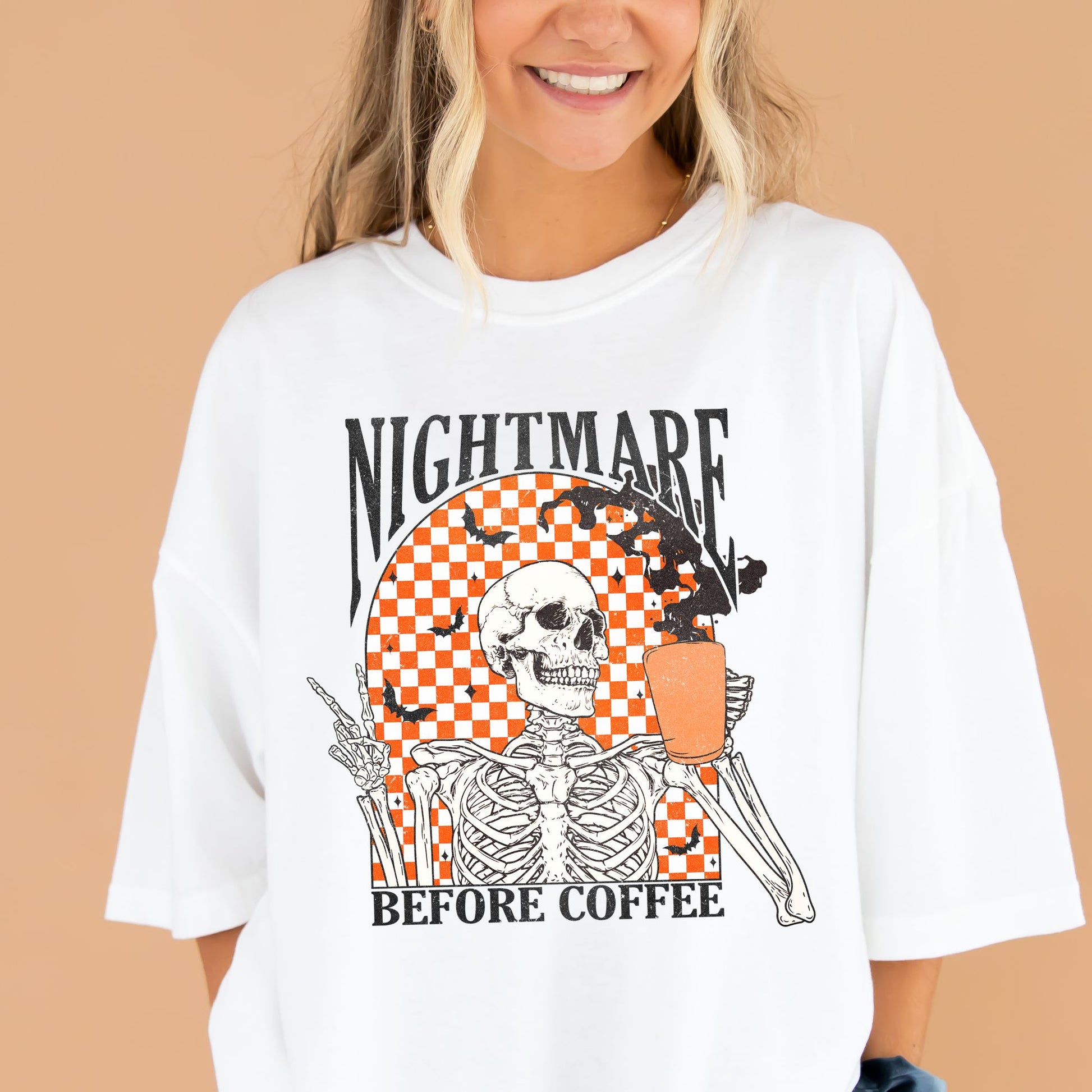 young woman wearing a white comfort colors t-shirt with a nightmare before coffee skeleton/bat print with a checkered background