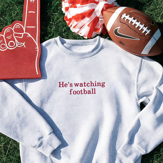 ash crewneck sweatshirt with custom he's watching football embroidered design on the center chest