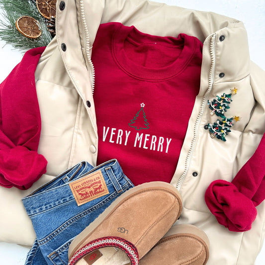 red crewneck sweatshirt with custom very merry outlined Christmas tree embroidered design in ivy green and white