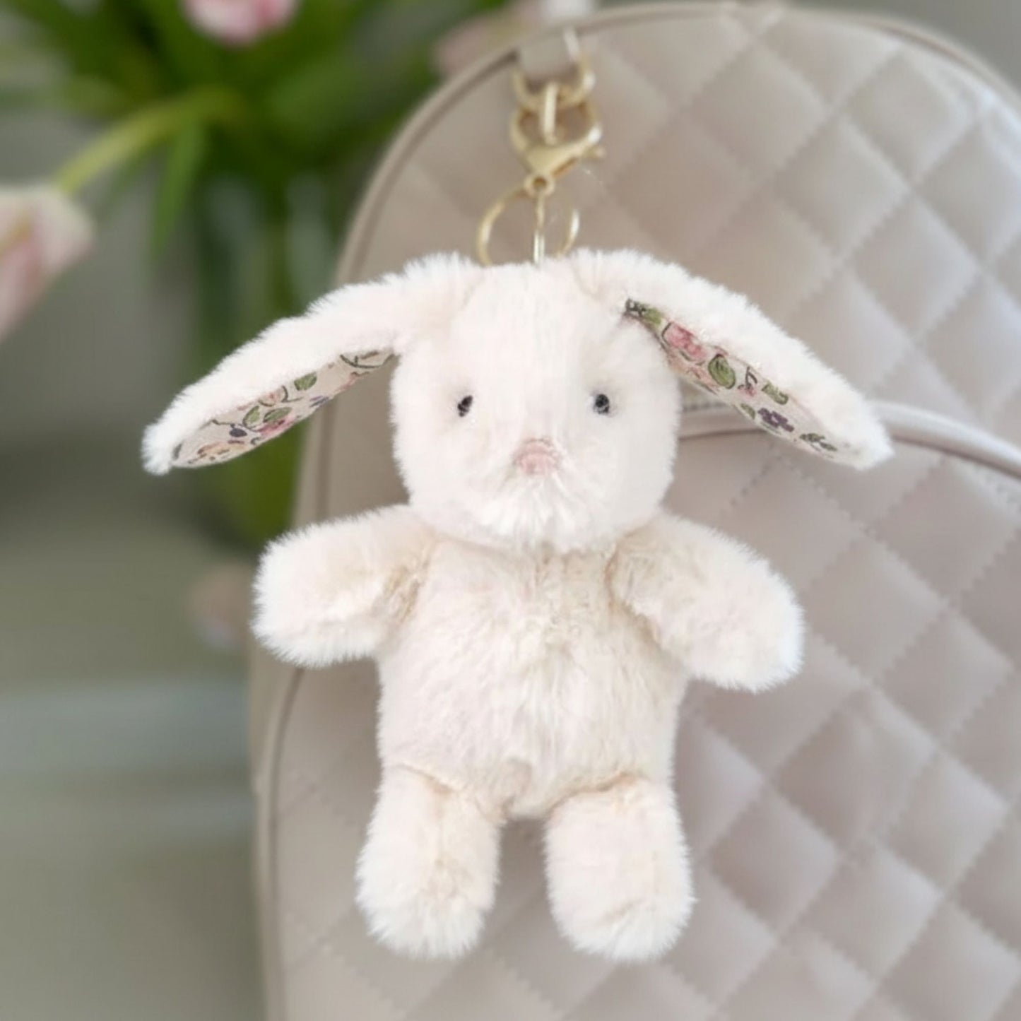 cream bunny bag charm hanging on a backpack