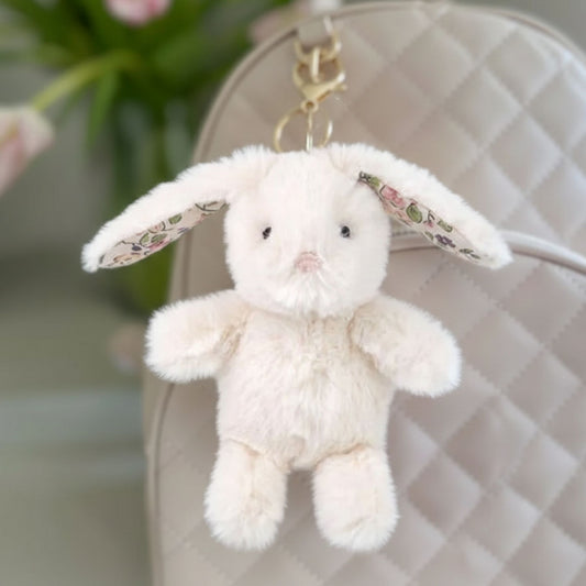 cream bunny bag charm hanging on a backpack