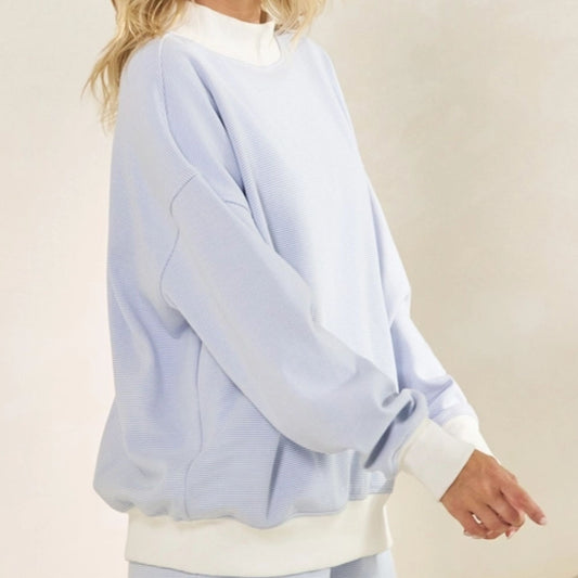 Light blue sweater over a white shirt on a neutral background