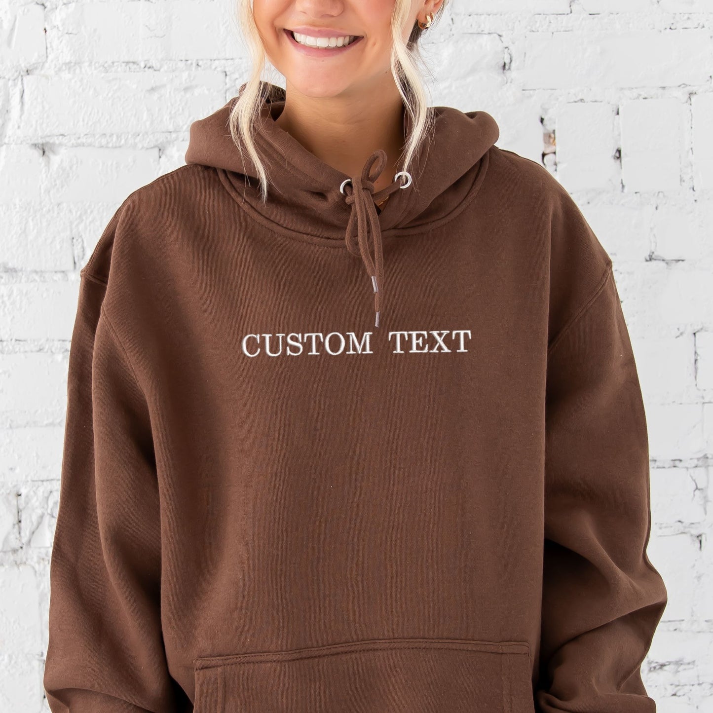 young woman wearing a chestnut hoodie with custom text in white thread