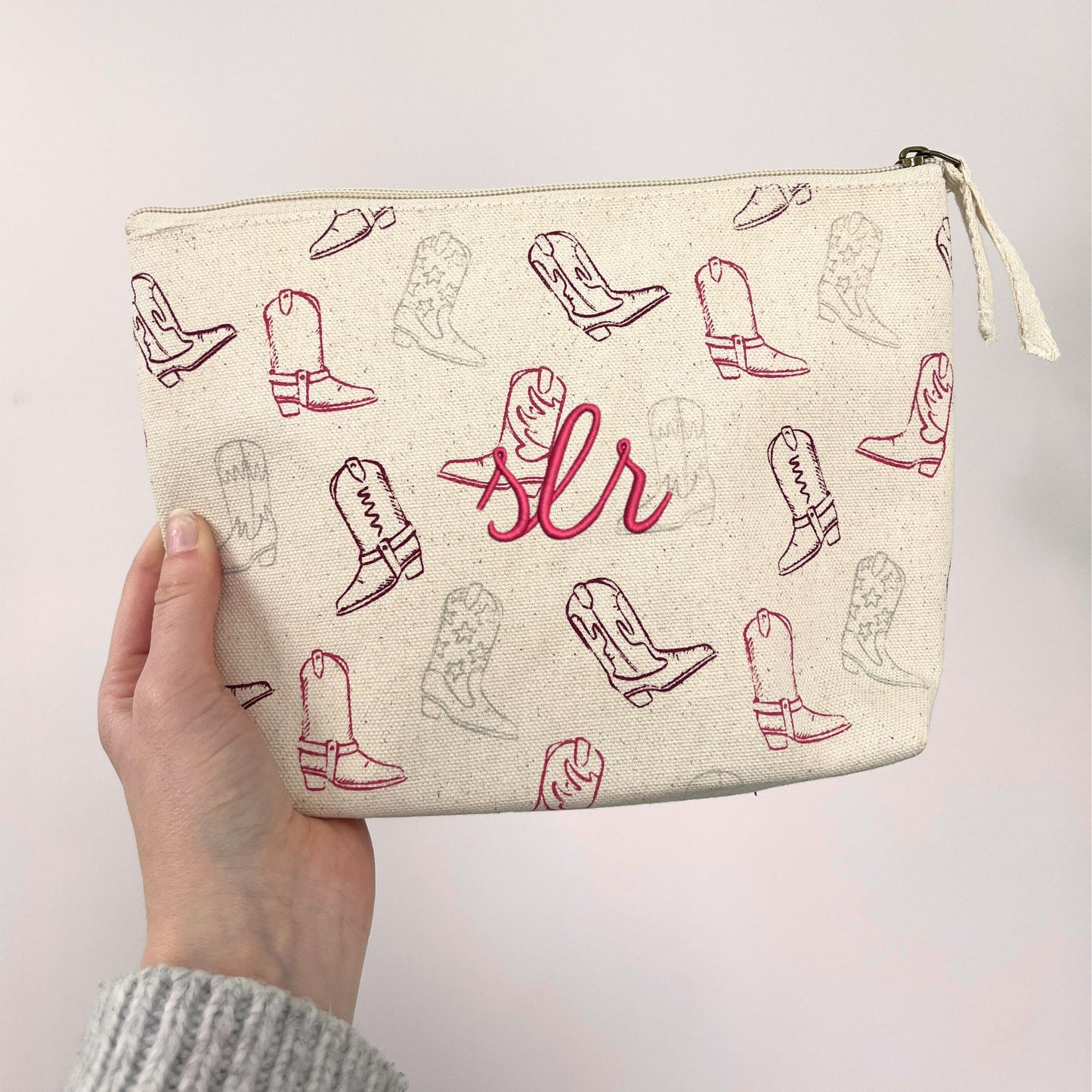 makeup pouch with cowgirl boot print on a natural cotton canvas featuring a custom initial monogram embroidery in raspberry thread