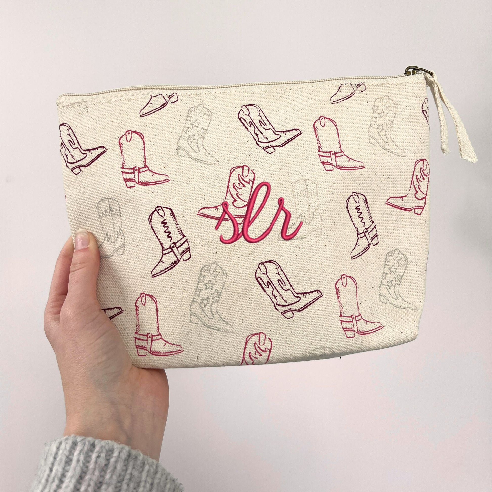 makeup pouch with cowgirl boot print on a natural cotton canvas featuring a custom initial monogram embroidery in raspberry thread
