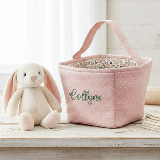 Pink polka dot storage basket with floral interior next to a plush bunny toy on a wooden surface.