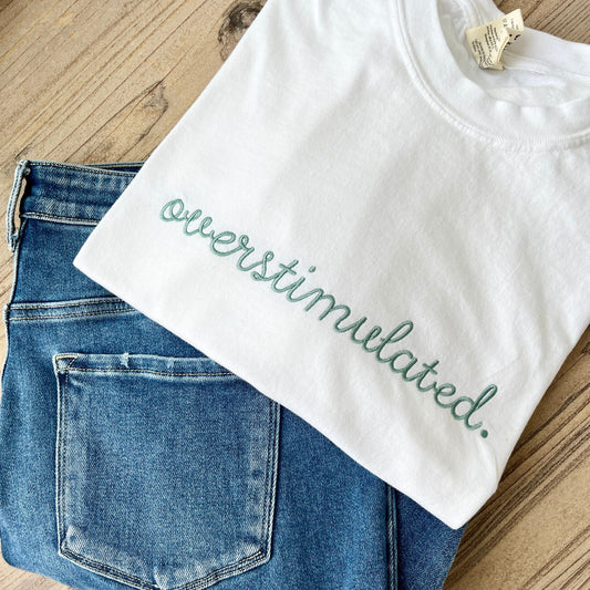 white comfort colors t-shirt with custom overstimulated embroidered design on the center chest in eucalyptus thread