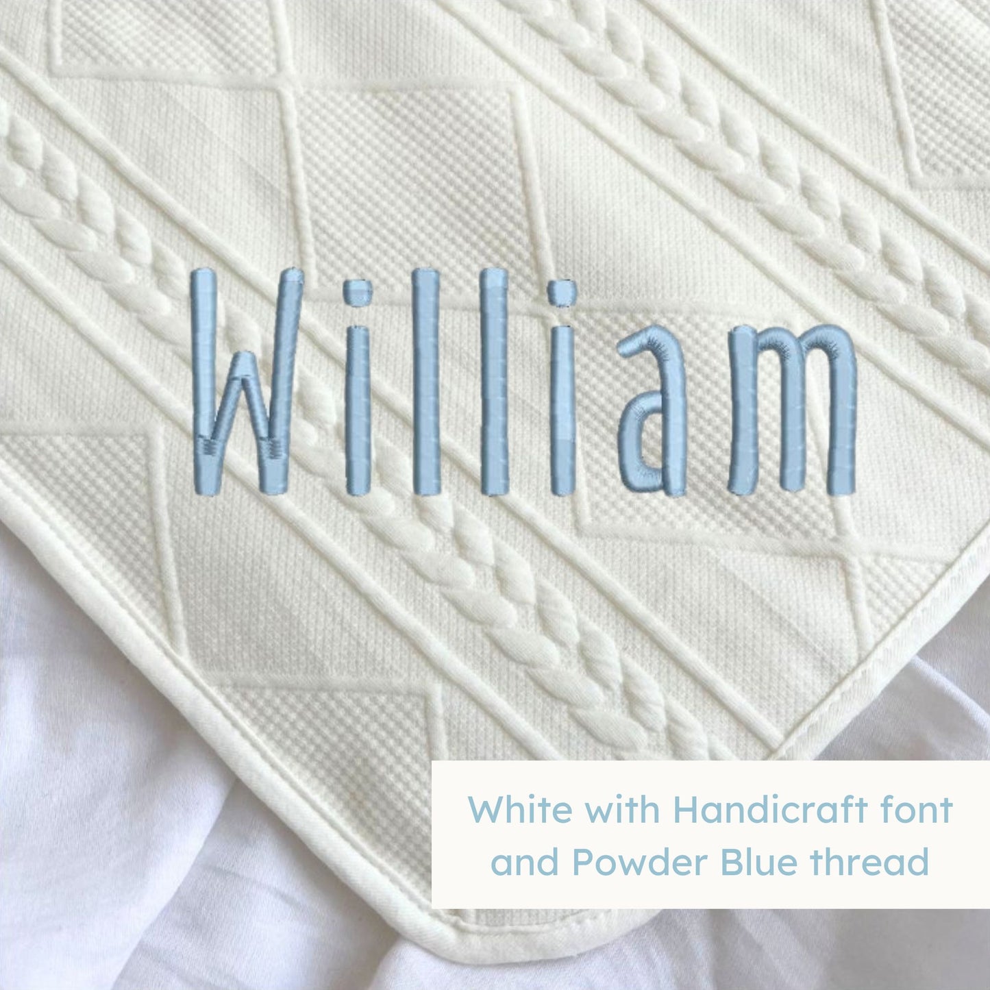 A white knitted blanket with a personalized name embroidered on the corner