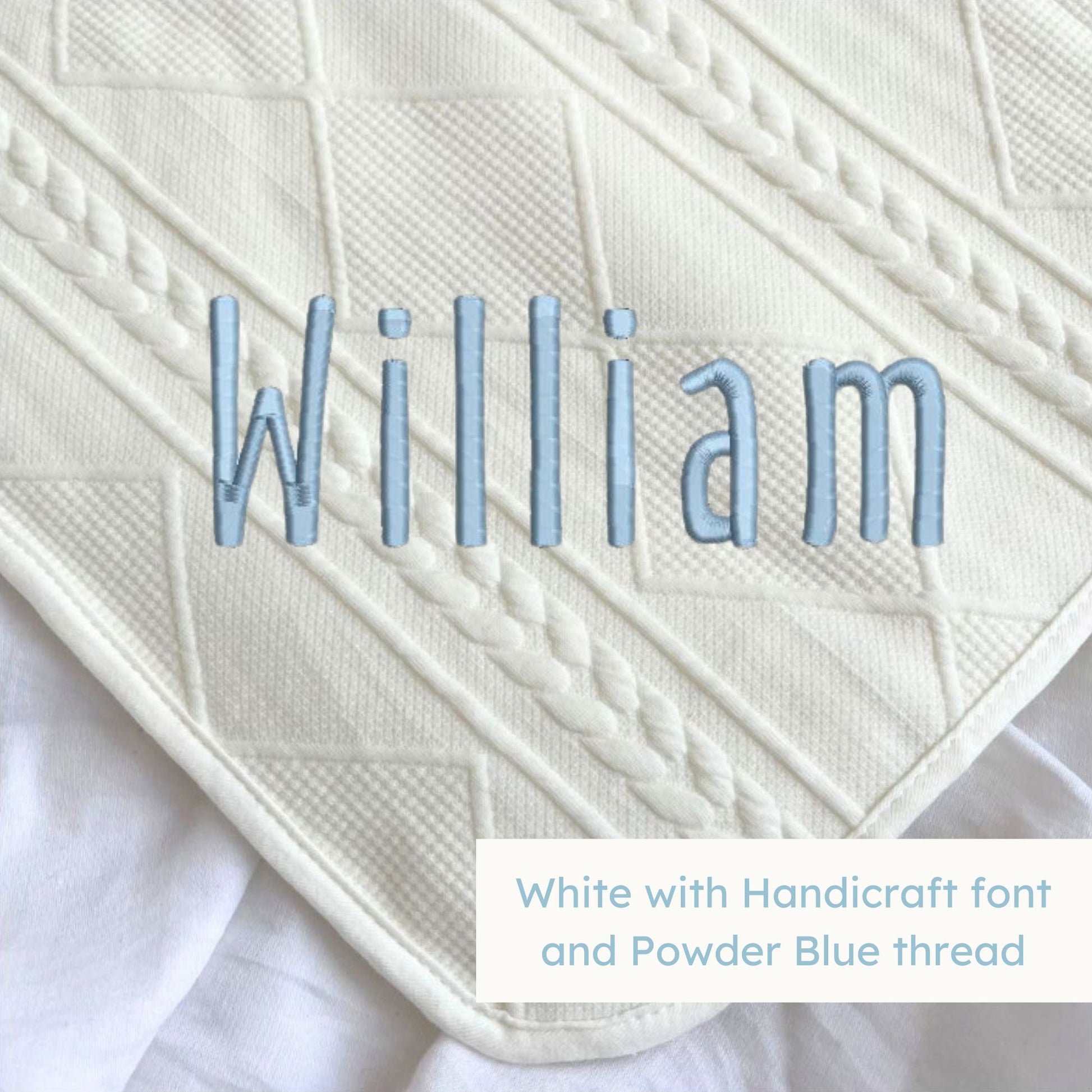 A white knitted blanket with a personalized name embroidered on the corner