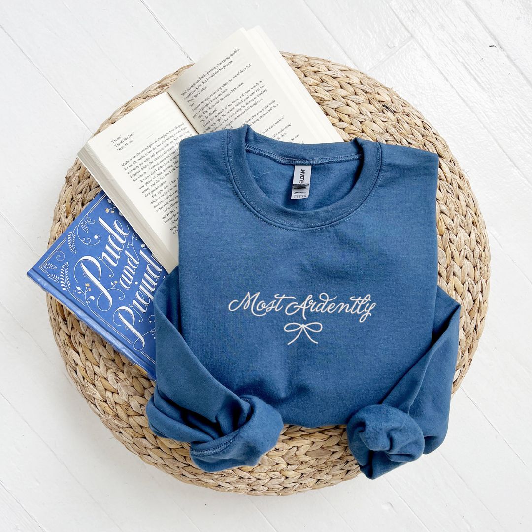 indigo crewneck with embroidered Most Ardently and bow design in white thread