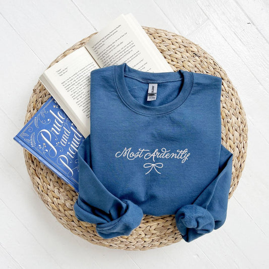 indigo crewneck with embroidered Most Ardently and bow design in white thread