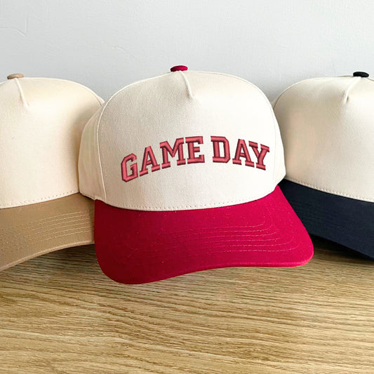 beige, red, and black two tone trucker hat with custom game day embroidered design