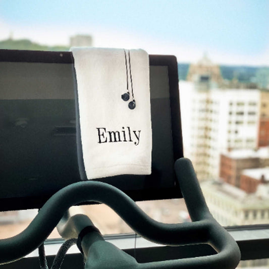 White gym towel with custom name embroidery draped over treadmill