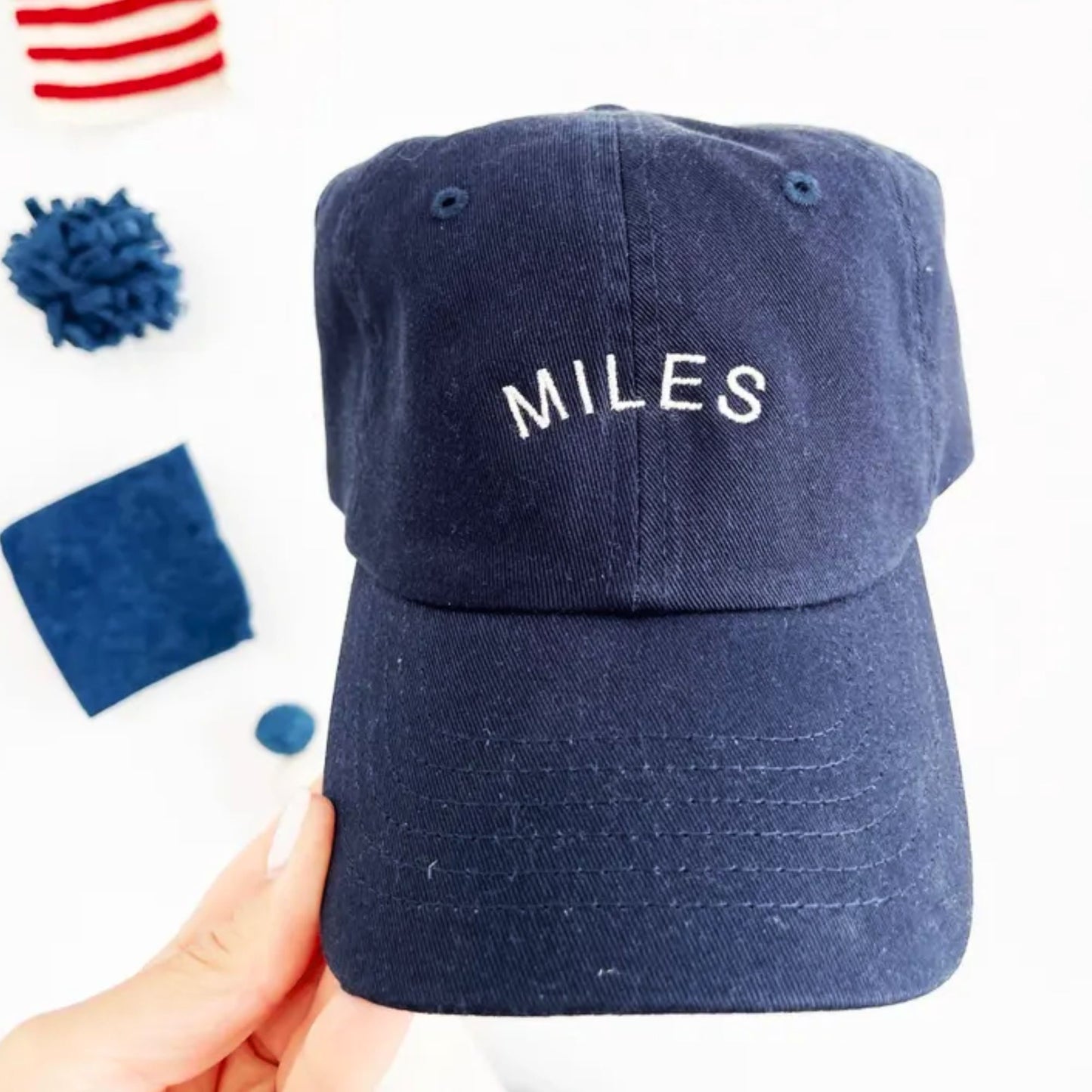 May include: A navy blue baseball cap with a white embroidered word 'MILES' on the front.