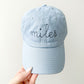  baby blue youth baseball cap with embroidered name in a stitched cursive font and navy thread