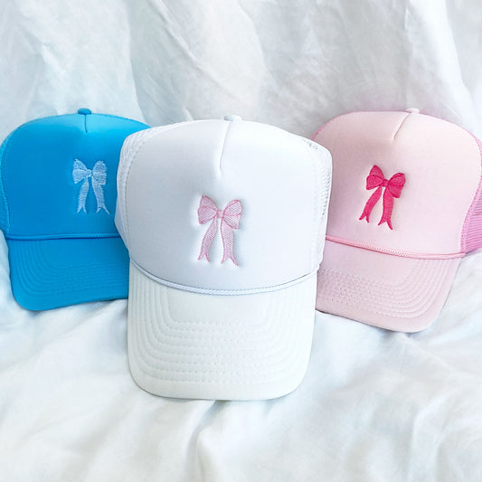 3 trucker hats in colors white pink and blue with embroidered bow design in white and pink threads
